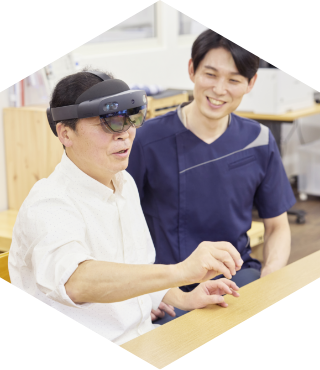 利用者がヘッドセットを用いてリハビリをし、スタッフが付き添っている様子